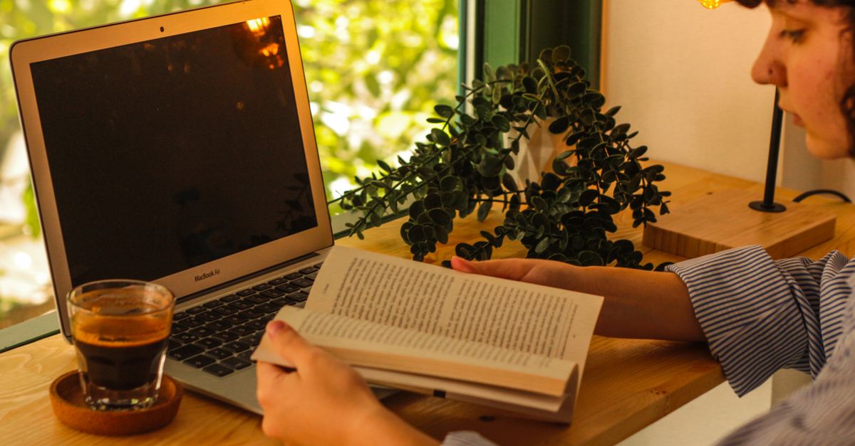 person reviewing finances on laptop with coffee, warm morning light, cozy home office