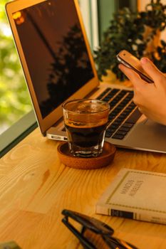 Cozy workspace with coffee, laptop, and smartphone on a bright morning.