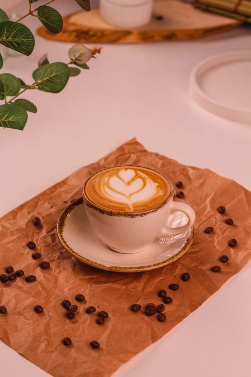 Free Elegant cappuccino with beautiful latte art on rustic background with coffee beans and cozy ambiance. Stock Photo