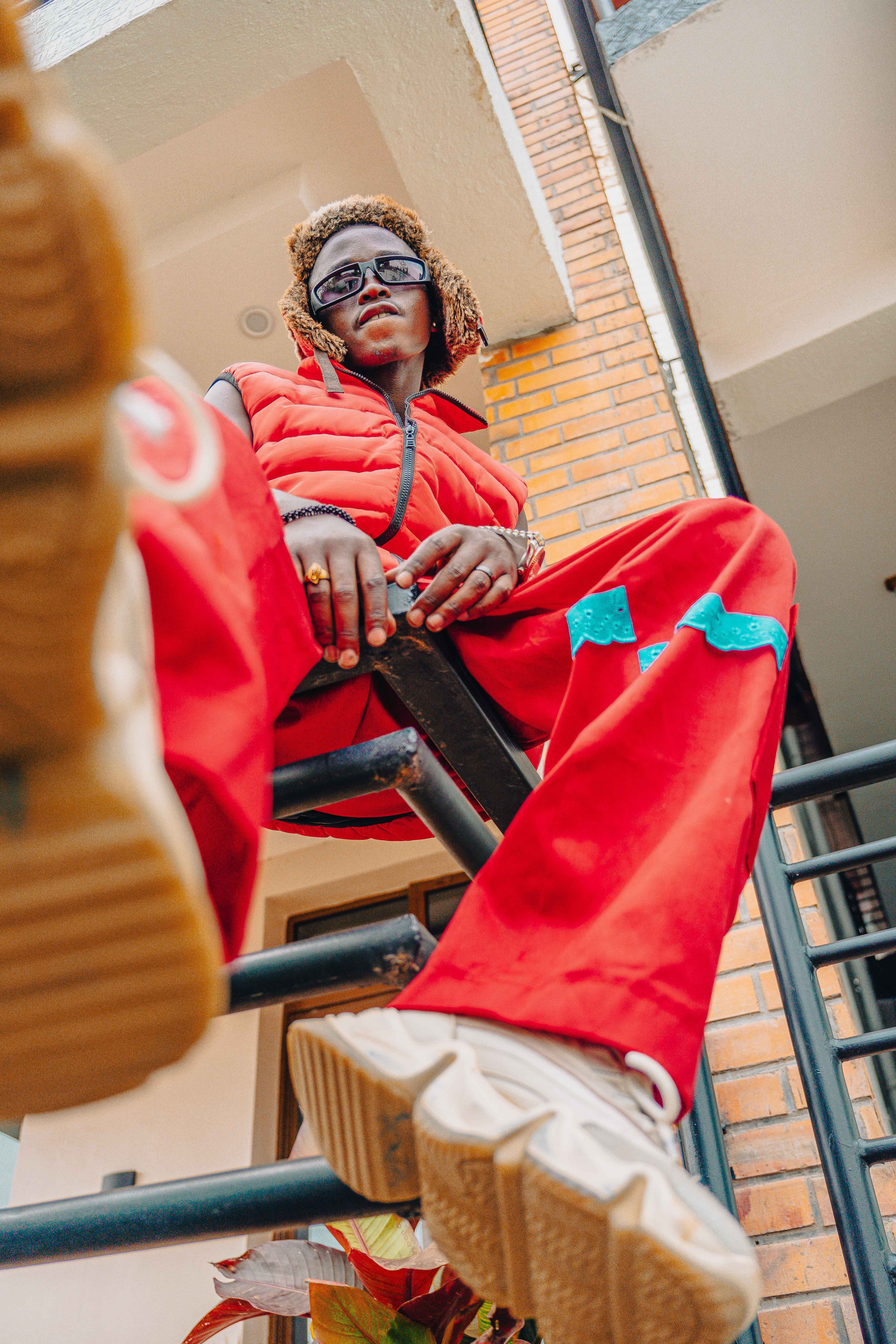 Fashionable individual in red attire poses with confidence in urban setting.