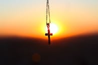 夕阳映照下，十字架吊坠的轮廓象征着信仰与和平