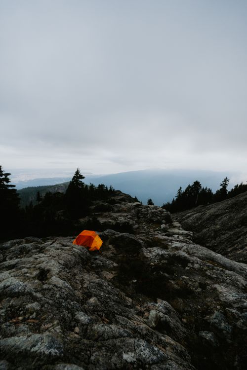 Free Lonely orange tent on rocky mountain under cloudy sky, perfect for adventure and travel themes. Stock Photo