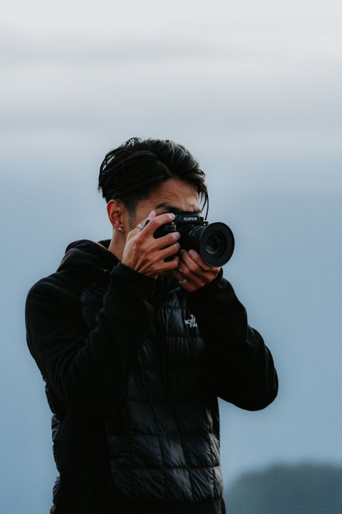 Free A young man in winter attire taking photos outdoors with a camera. Stock Photo