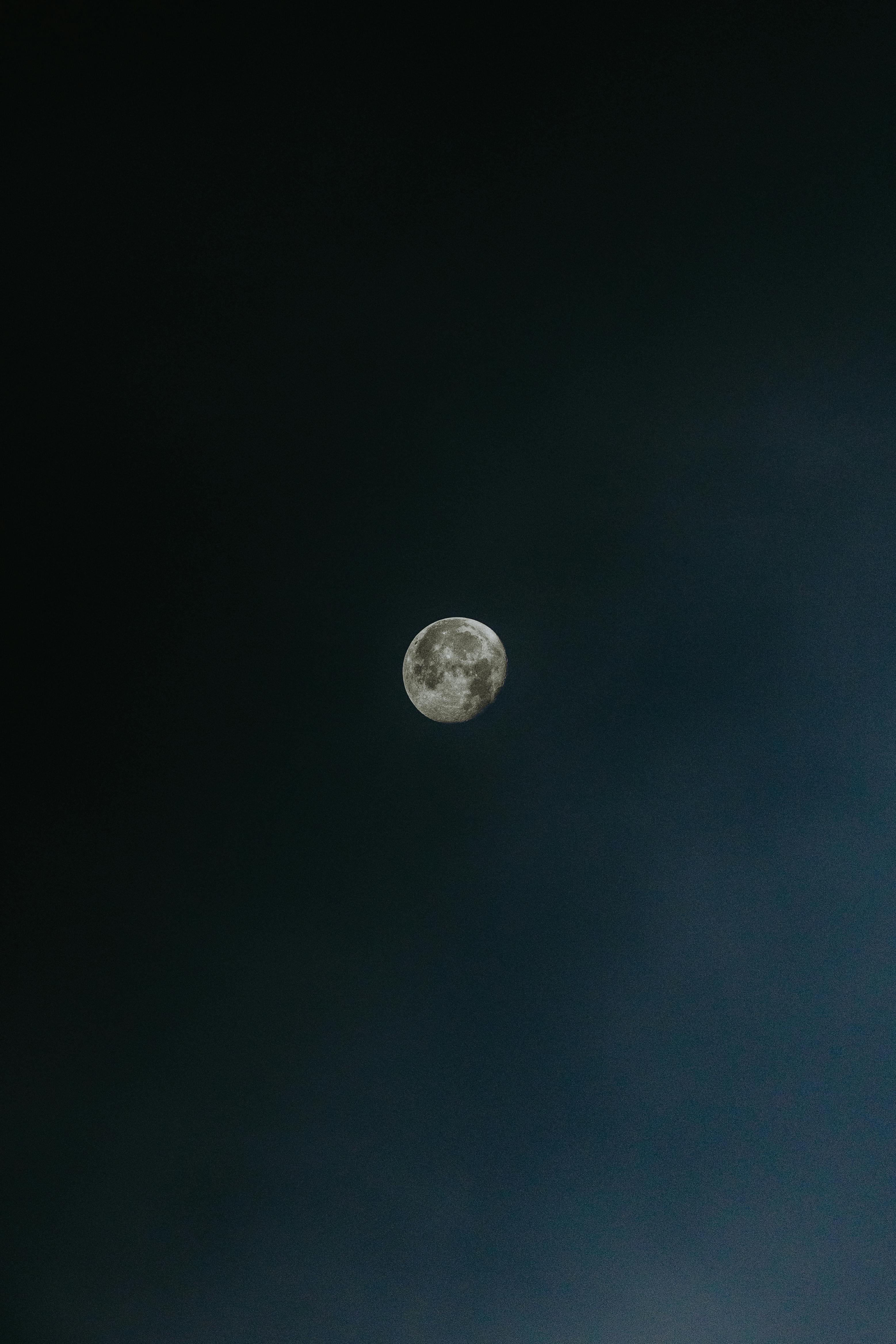 A full moon illuminating a slightly cloudy, dark night sky.