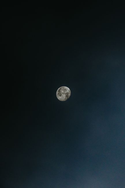 A full moon illuminating a slightly cloudy, dark night sky.