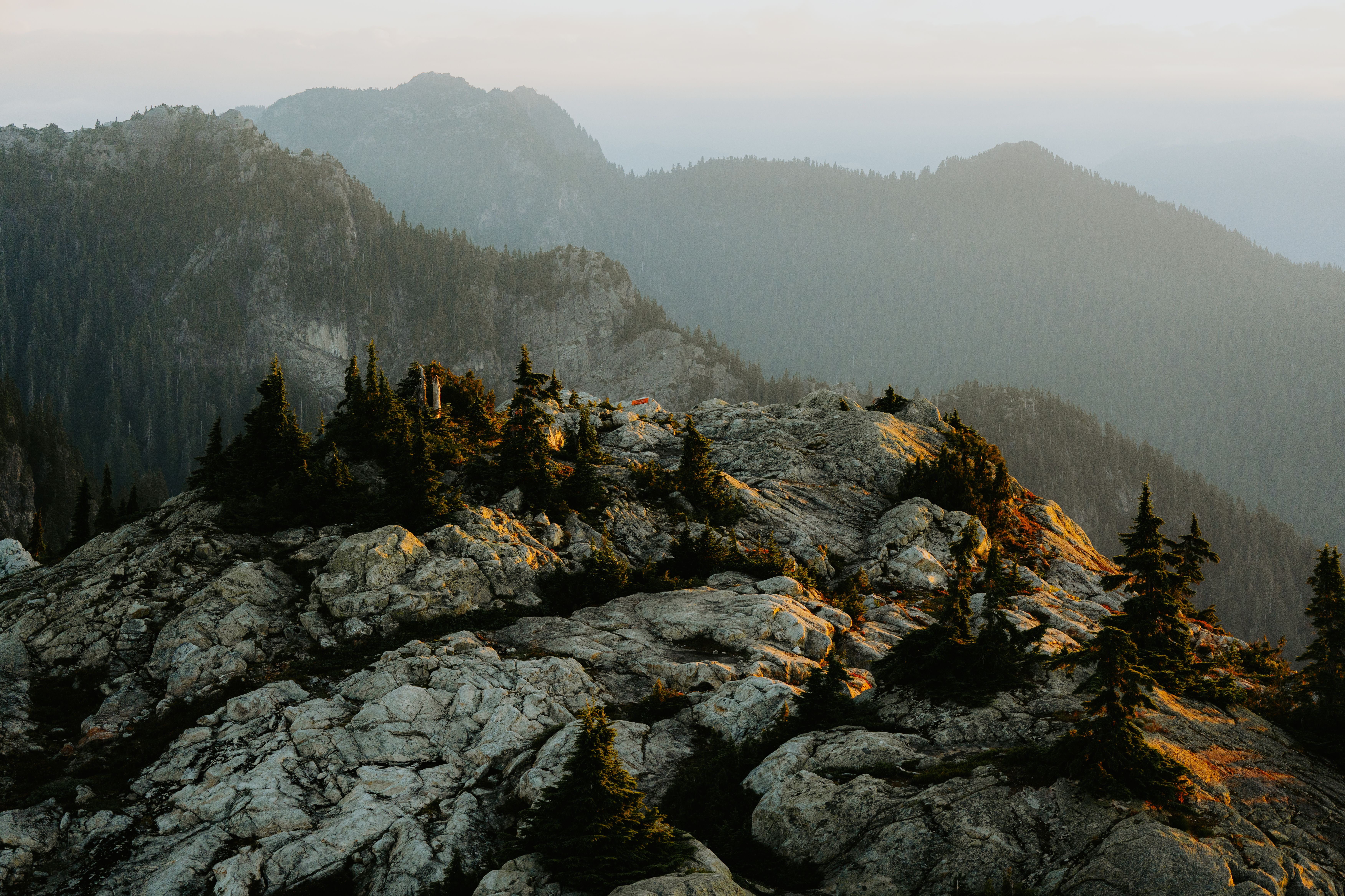 A mountain with trees and rocks at sunset · Free Stock Photo