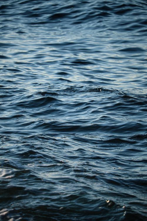 Free Close-up view of ocean waves creating abstract patterns in blue hues under summer light. Stock Photo