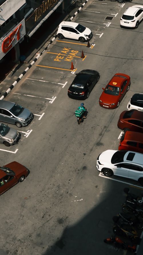 Free Aerial view of a busy parking lot with cars and a motorbike, in daylight. Stock Photo