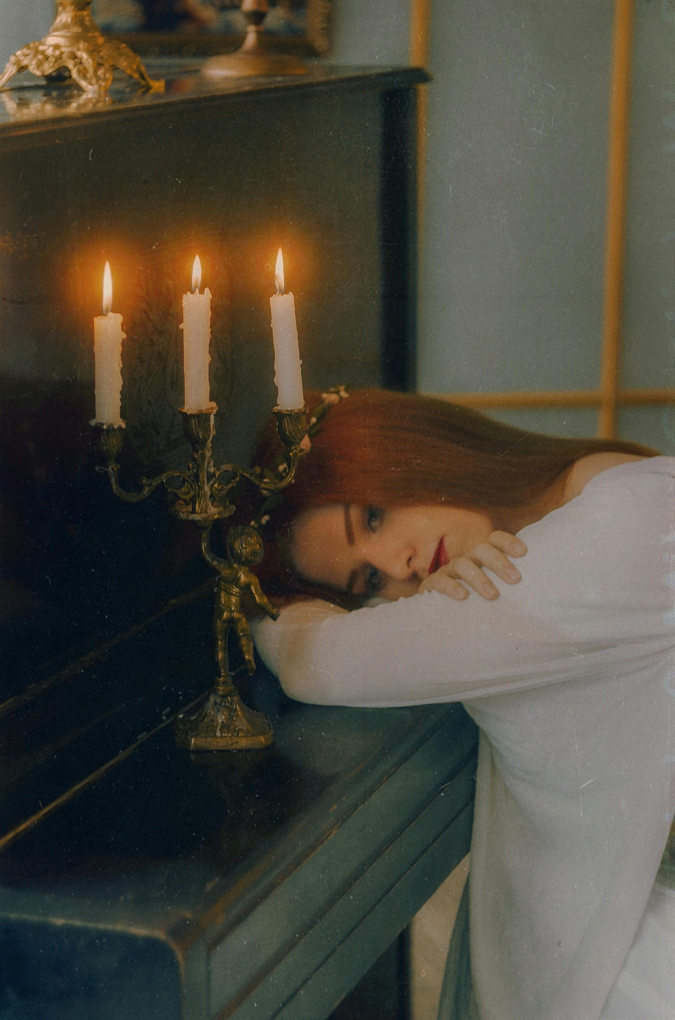 A serene portrait of a woman leaning on a piano lit by candlelight, creating a warm and peaceful atmosphere.
