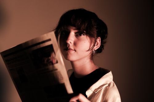 Free Moody portrait of a young woman holding a newspaper in sepia tones. Stock Photo