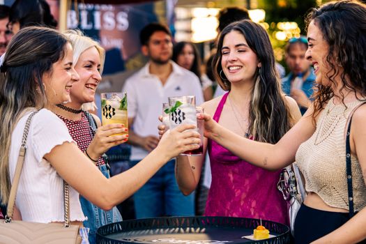 A group of young women enjoying drinks and friendship in an outdoor party setting.