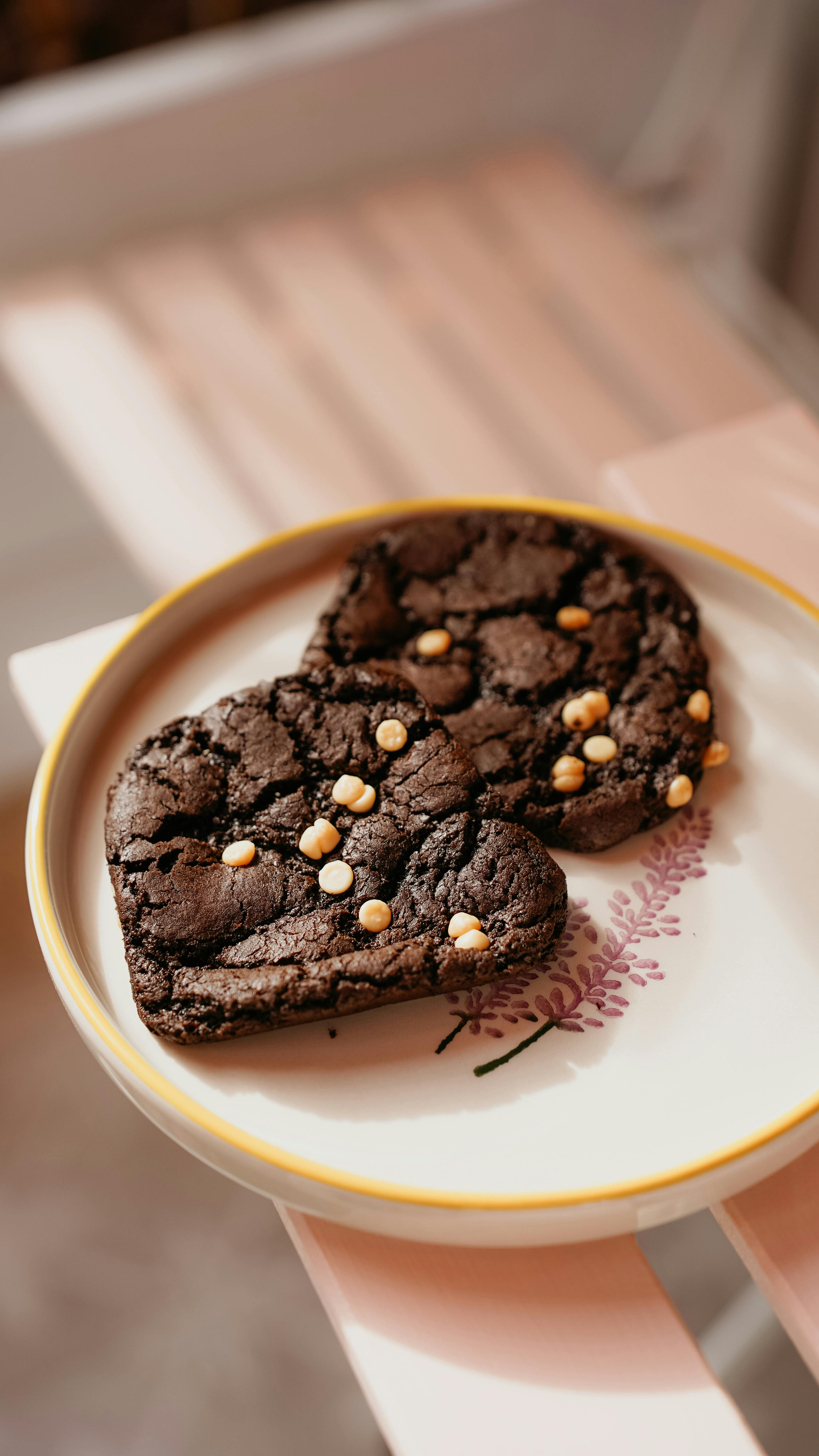 two chocolate cookies on a plate with gold sprinkles