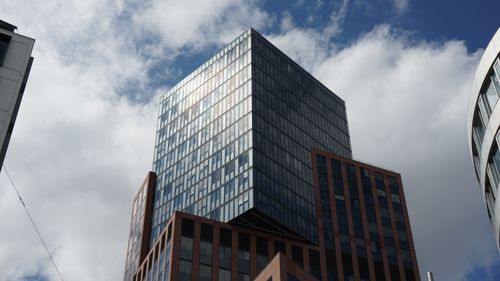 Free Contemporary urban skyscraper with reflective glass facade and blue sky background. Stock Photo