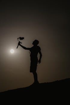 Silhouette of a man with camera, capturing a scenic sunset at Marsa Alam.