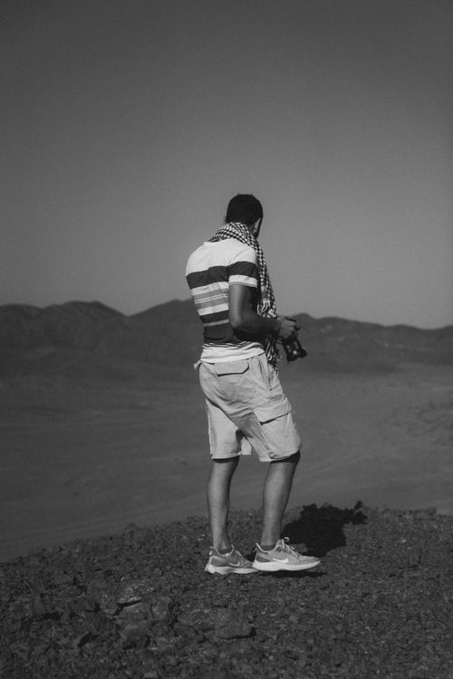 Free A man with a camera stands on a rocky hill in Marsa Alam, Egypt, capturing the vast desert landscape. Stock Photo