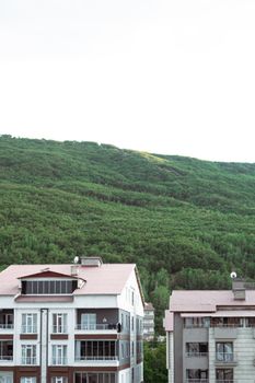 Urban residential buildings framed by lush green hills, perfect for nature and architecture themes.
