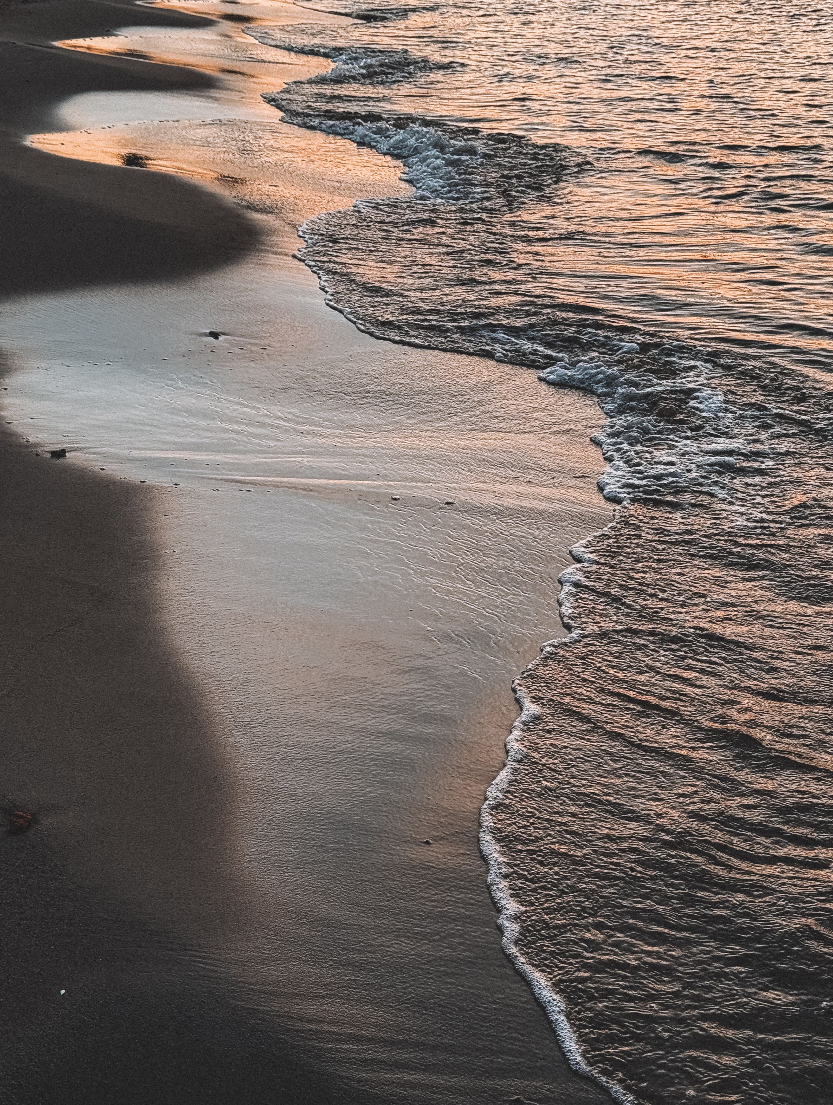 A sunset on the beach with waves and sand · Free Stock Photo