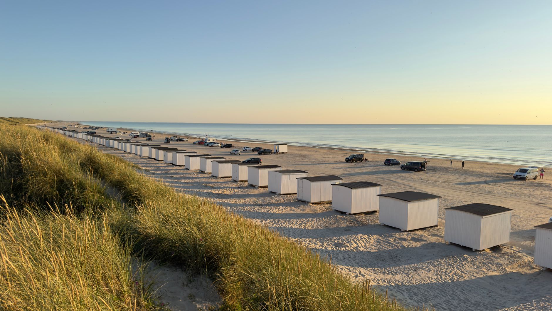 Beautiful sunset at Løkken Beach, Denmark, featuring iconic beach huts and serene ocean views.