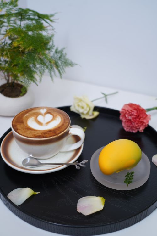Free A flat lay of cappuccino and dessert on a tray with florals, perfect for a cozy morning vibe. Stock Photo