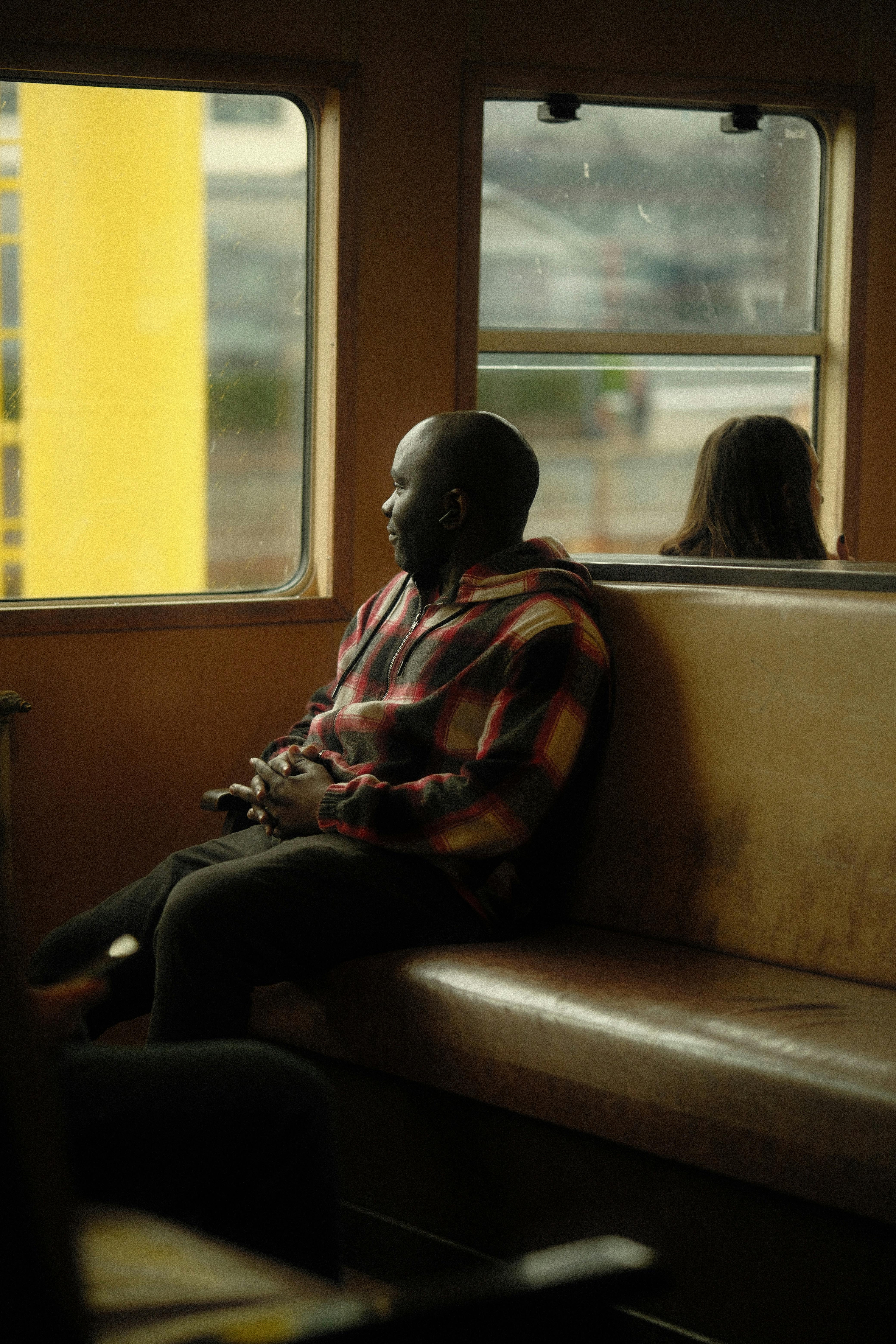 Man sitting on a train in İstanbul, gazing thoughtfully out the window.