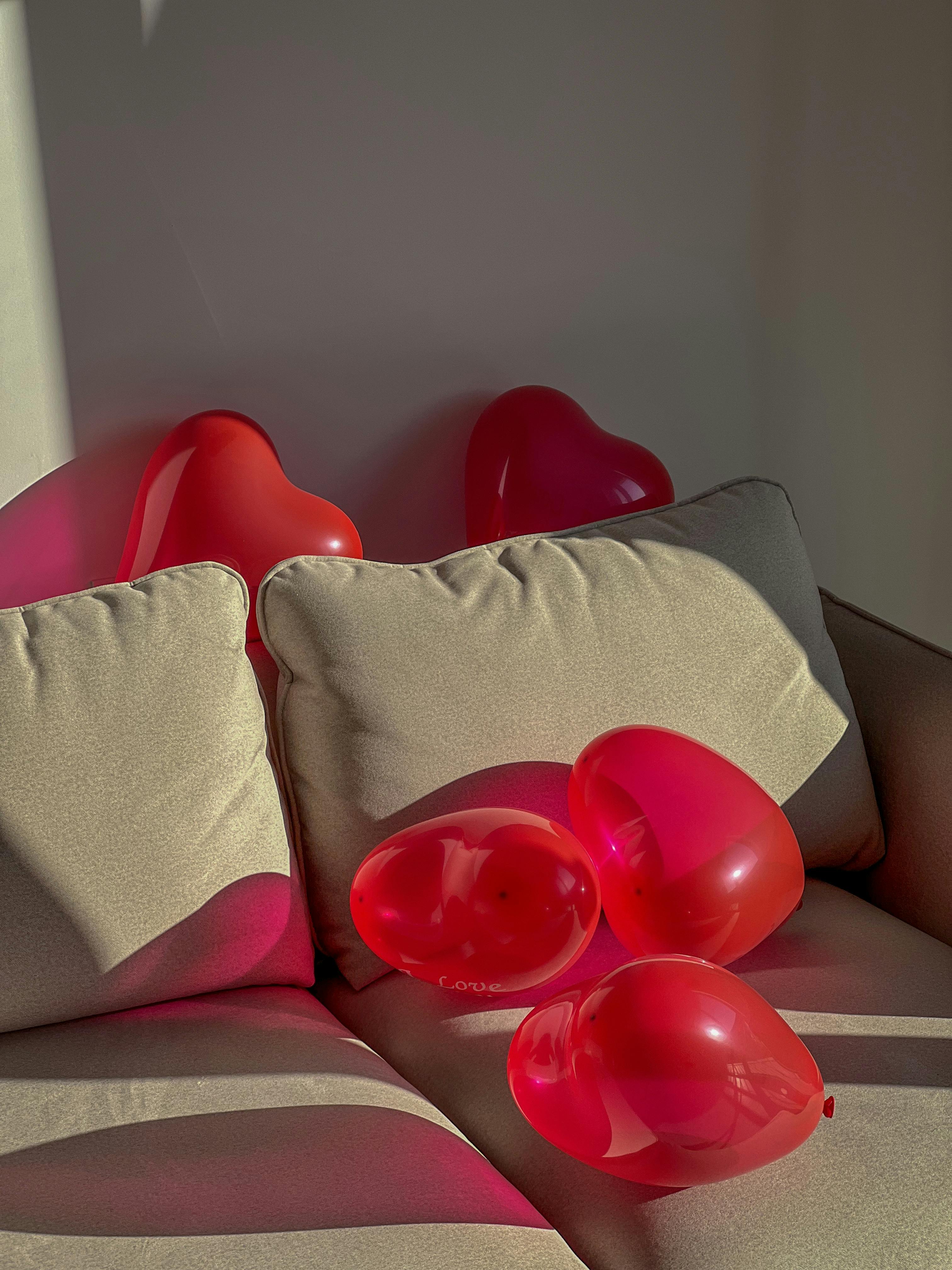 Heart-shaped red balloons on a sofa create a romantic, cozy ambiance.