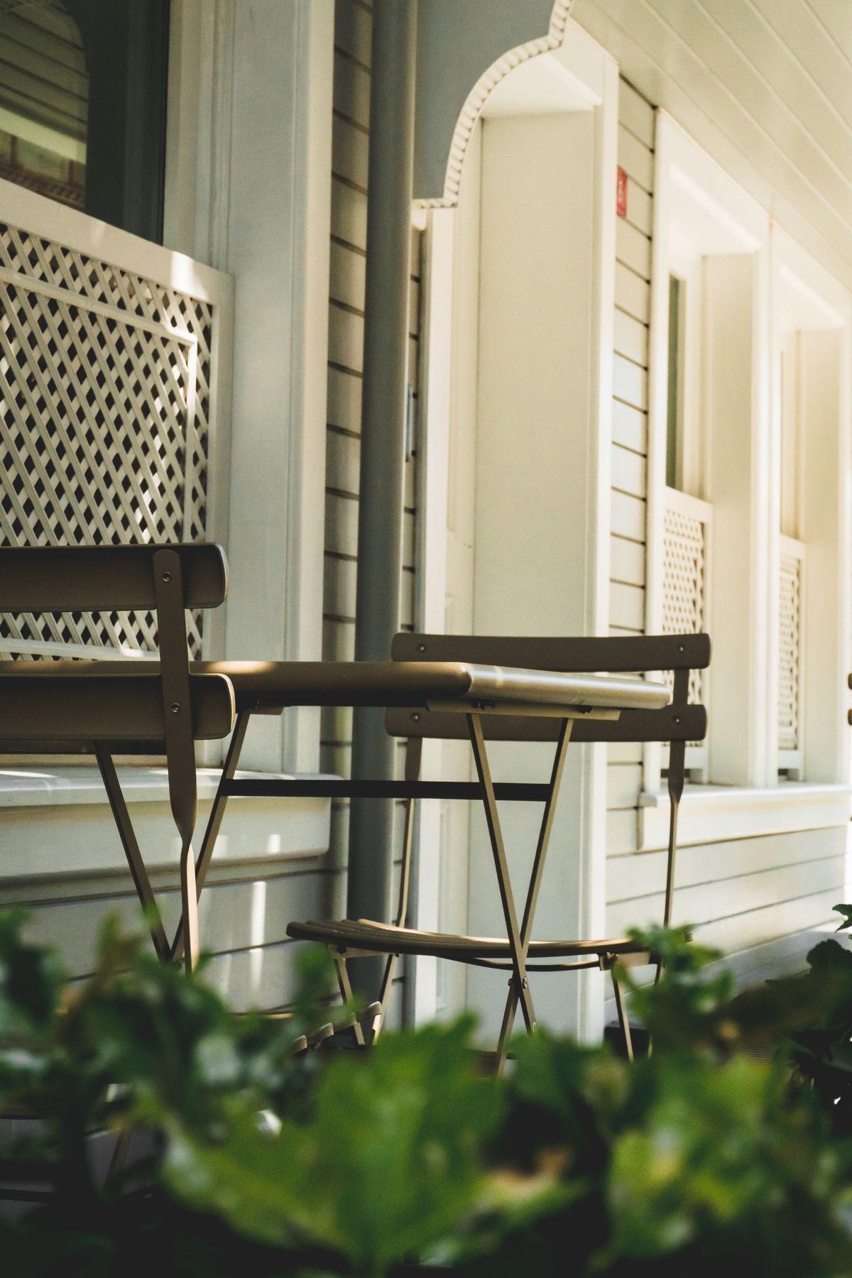 Inviting outdoor patio featuring vintage metal chairs and table under daylight. Stock Photo.