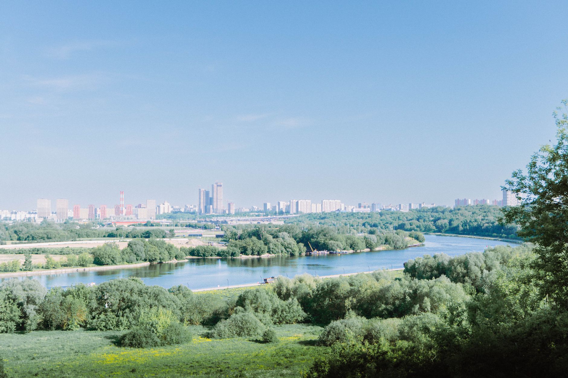 Breathtaking panoramic view of Moscow's skyline with a river and lush greenery under a clear sky.