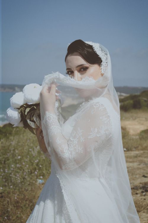 Free A beautiful bride in lace dress and veil with a flower bouquet, outdoors in summer. Stock Photo