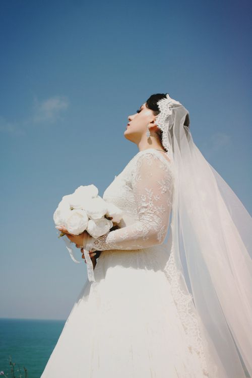 A bride standing on a cliff with her veil · Free Stock Photo