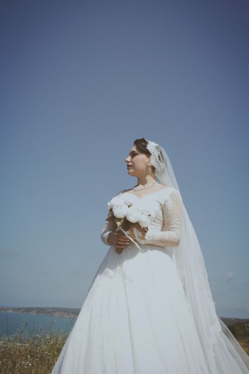 Free A serene outdoor portrait of a bride in a white dress holding a bouquet. Stock Photo