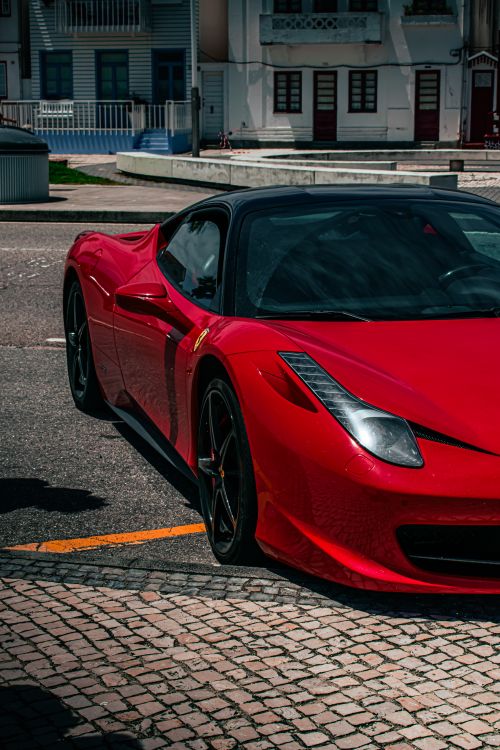 Free A vibrant red sports car parked on an urban street, showcasing luxury and style. Stock Photo