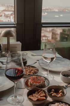 An elegant dining table setup with wine glasses filled with red and white wine, surrounded by assorted appetizers.