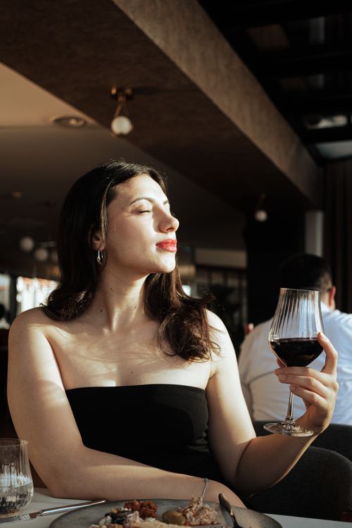 A woman in a black dress is holding a glass of wine · Free Stock Photo