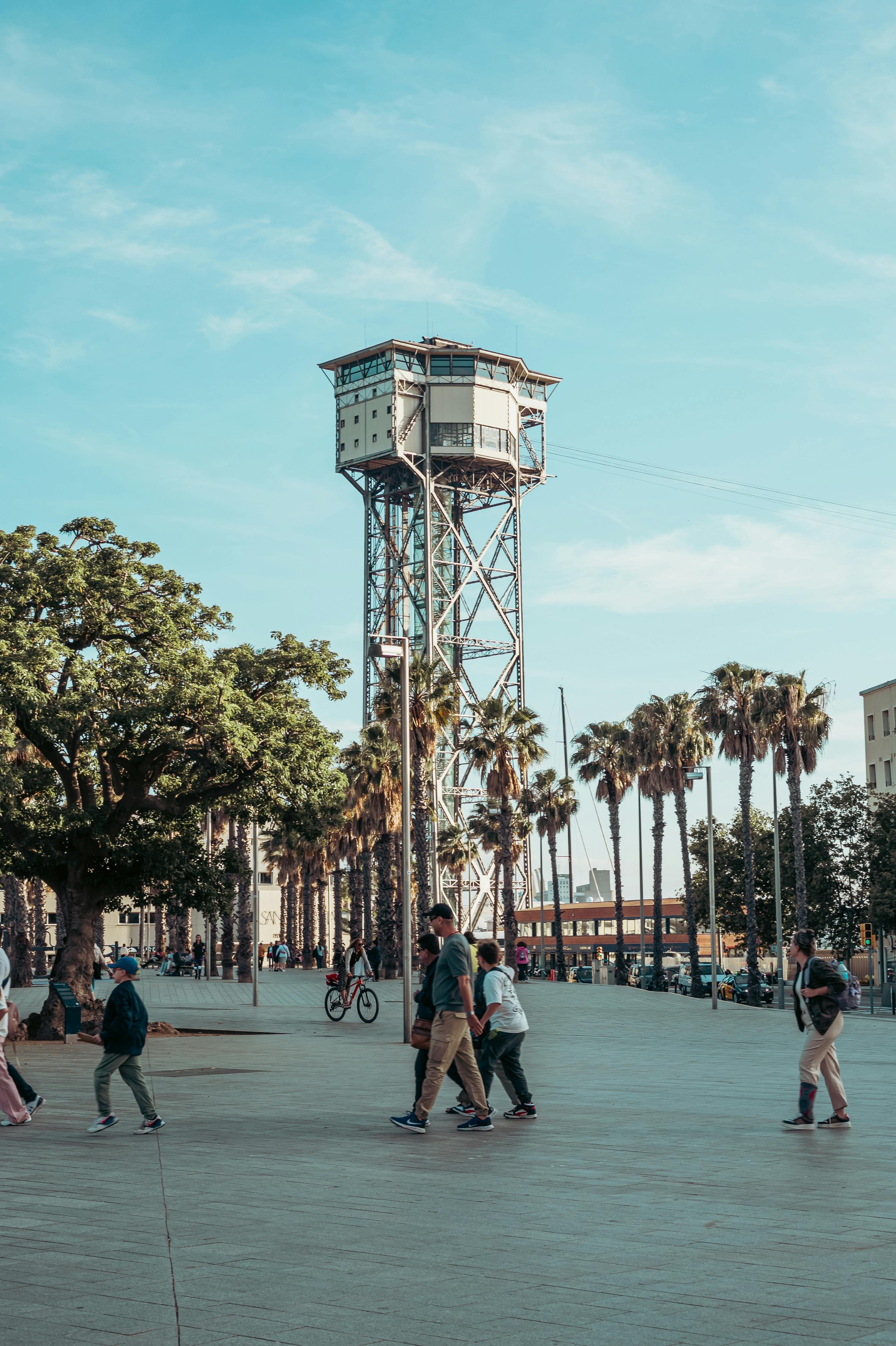 people walking around a plaza with a water tower in the background