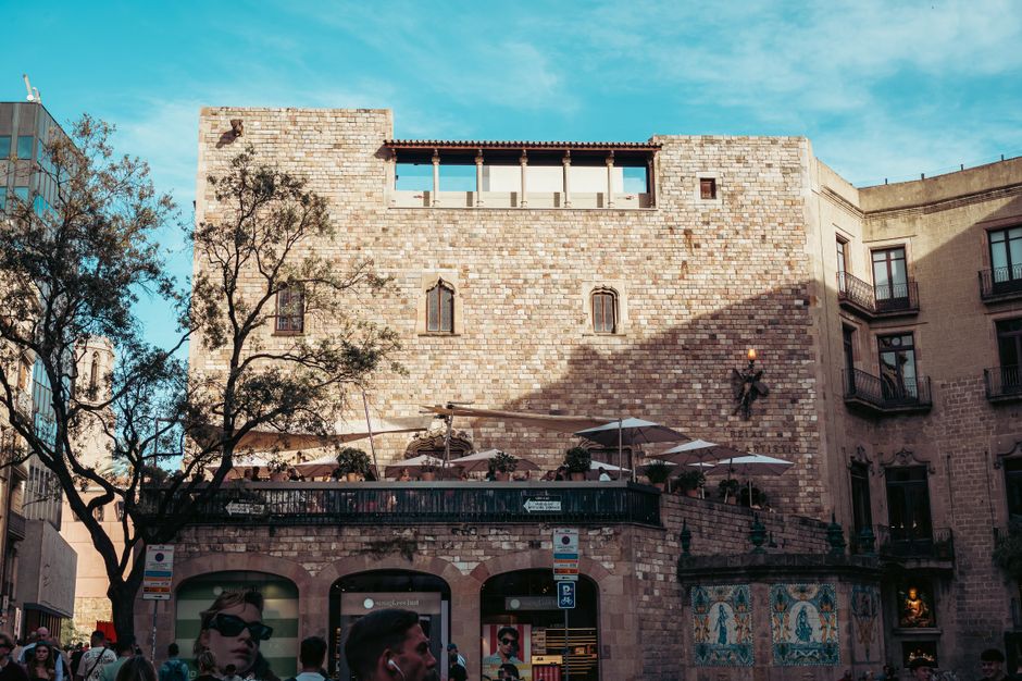 Sunlit historic stone building in Barcelona's urban plaza captured during a bright day.