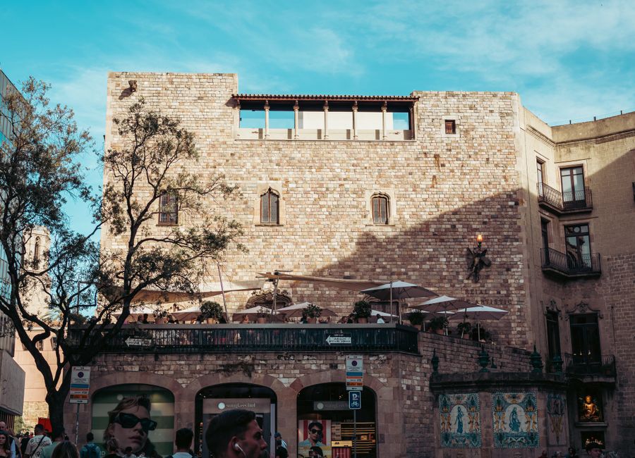 Sunlit historic stone building in Barcelona's urban plaza captured during a bright day.