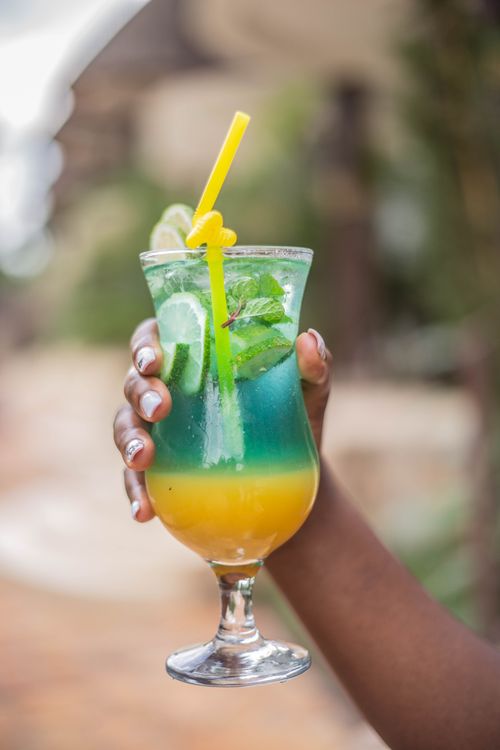 Free Vibrant tropical cocktail in a glass with mint, lime, and a straw, perfect for summer refreshment. Stock Photo