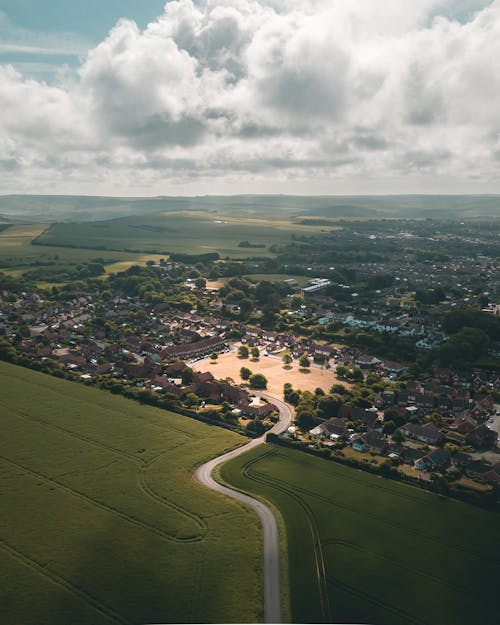 Free High-angle Photo Of A Town Near A Agricultural Land Under White Clouds Stock Photo