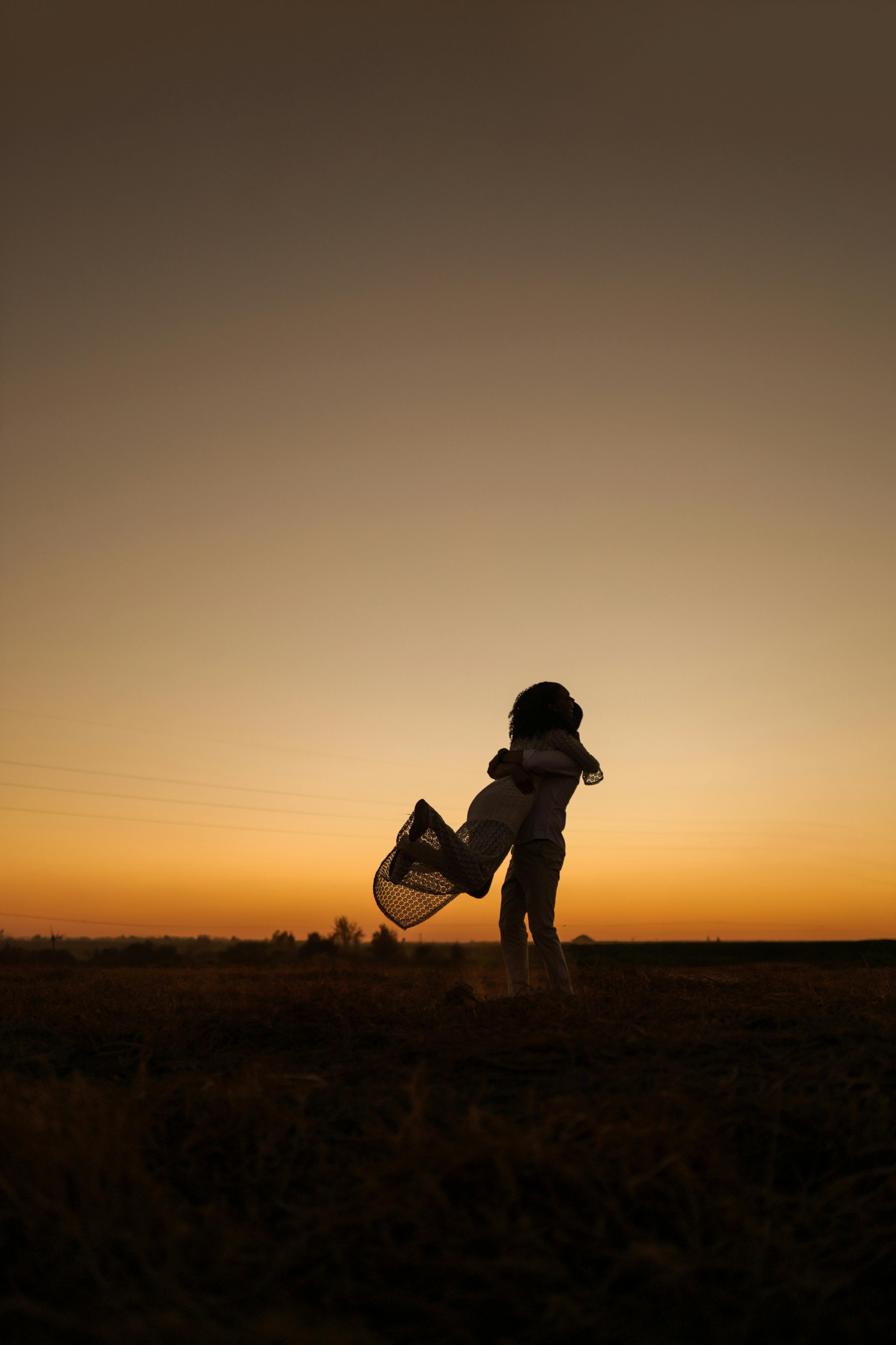 a silhouette of a person standing in a field at sunset