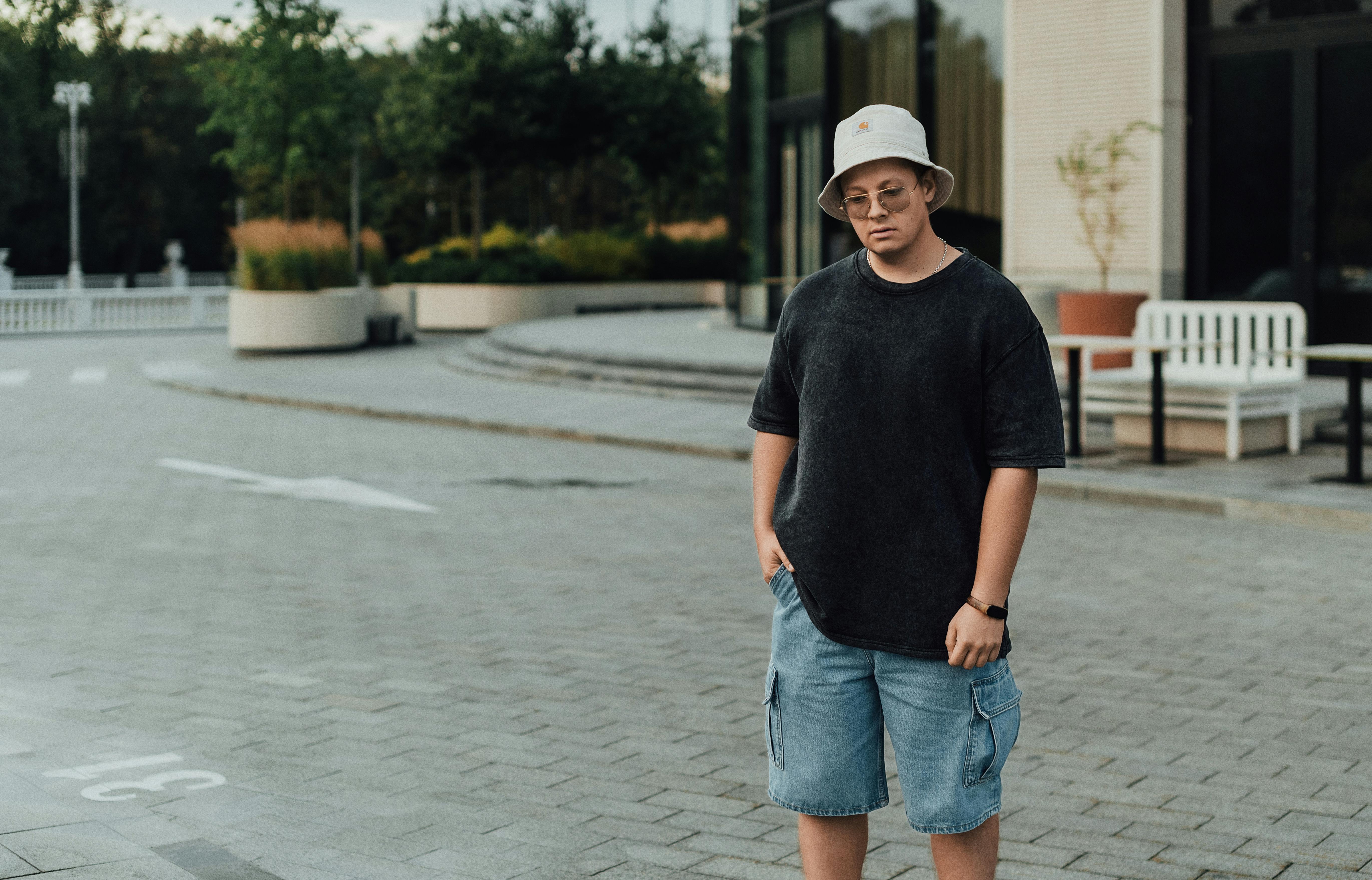 a man in shorts and a hat standing on a skateboard