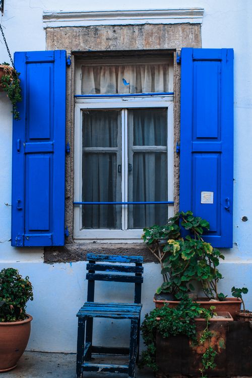 Free Charming rustic window with vibrant blue shutters and potted plants, offering a quaint exterior view. Stock Photo
