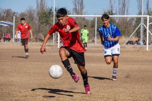 Boys playing an exciting soccer match outdoor on a sunny day.