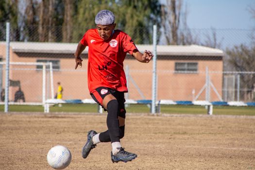 Young male soccer player skillfully dribbles the ball on a sunny day at an outdoor field.
