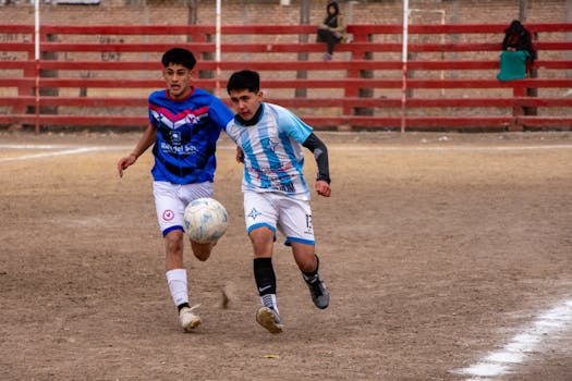 Two young soccer players compete intensely on an outdoor field, showcasing athleticism and energy.