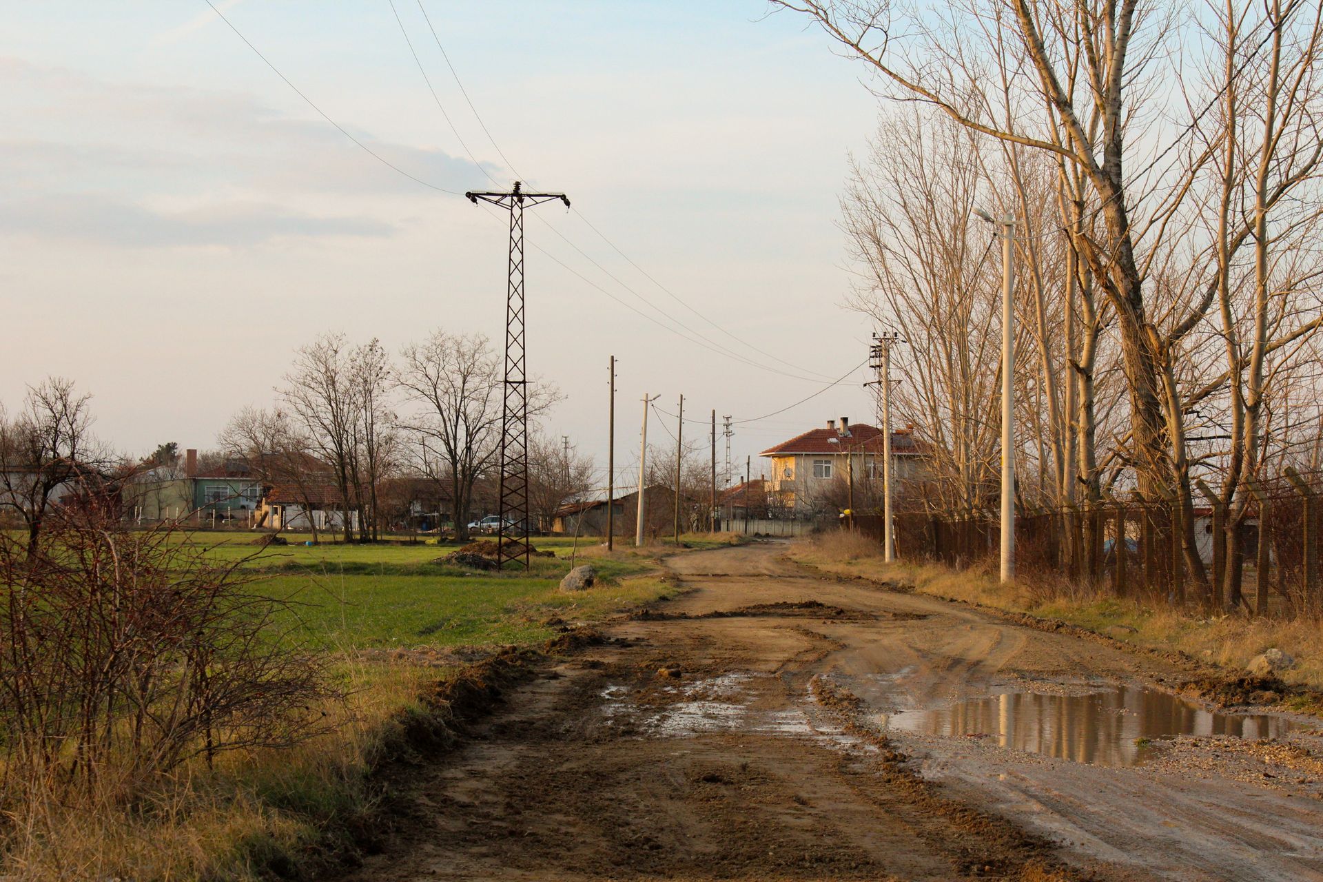 Yakılmış bir köyde alacakaranlıkta toprak yol ve harabe izleri