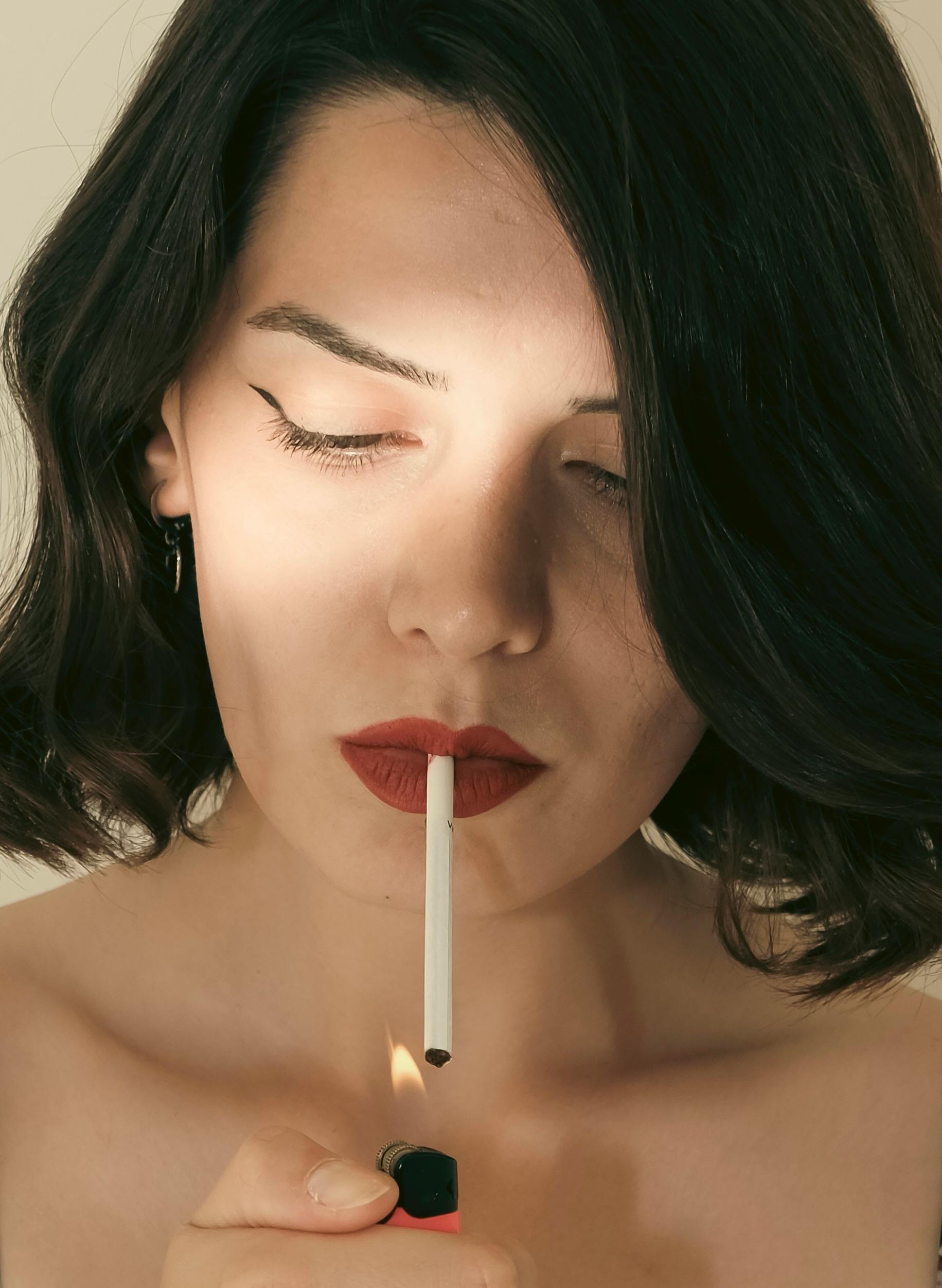 a woman with red lipstick is holding a cigarette