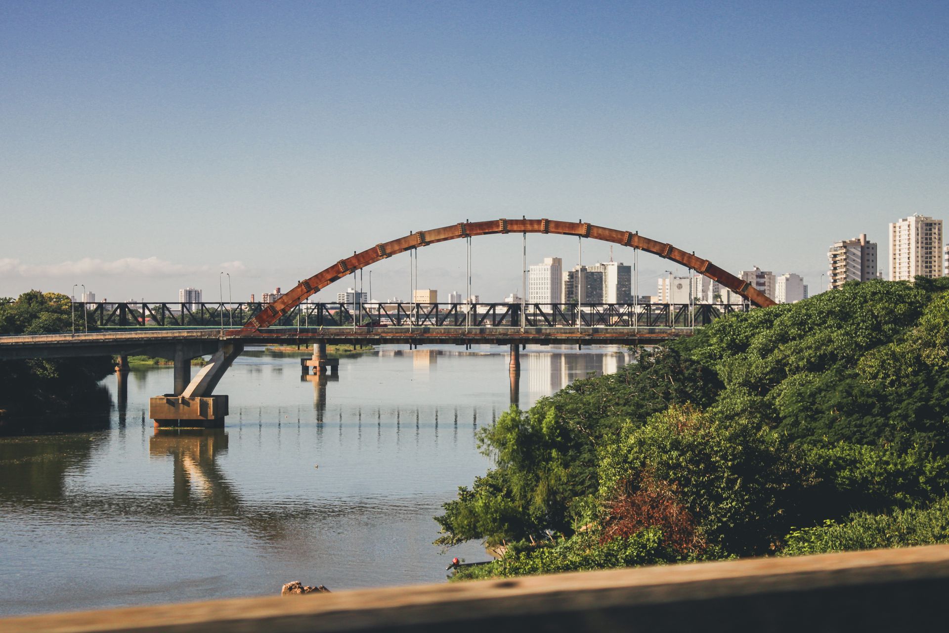 Scenic bridge view in Campos dos Goytacazes, Brazil with city skyline reflections.