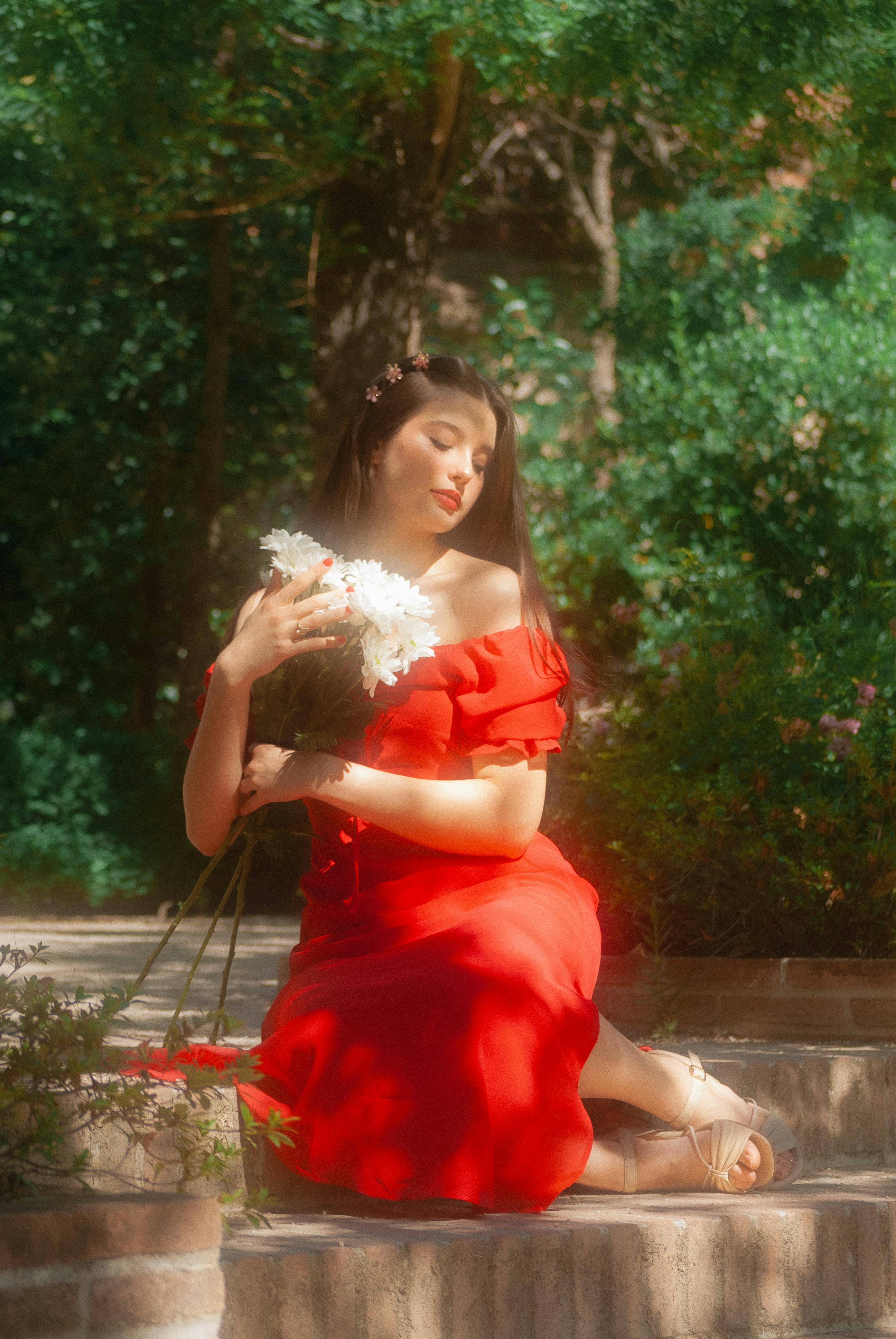 a woman in a red dress sitting on some steps