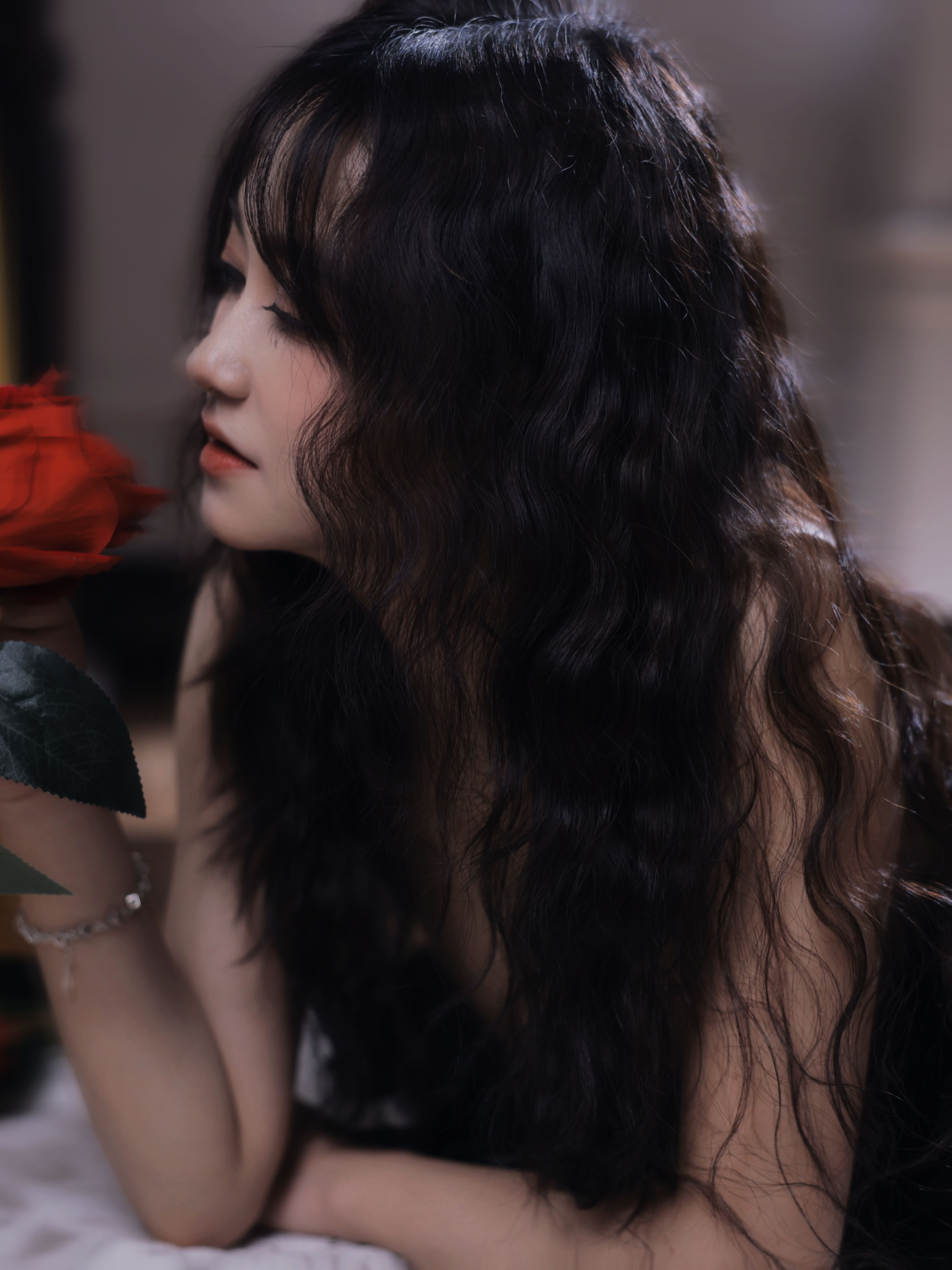 A woman with long black hair holding a red rose · Free Stock Photo