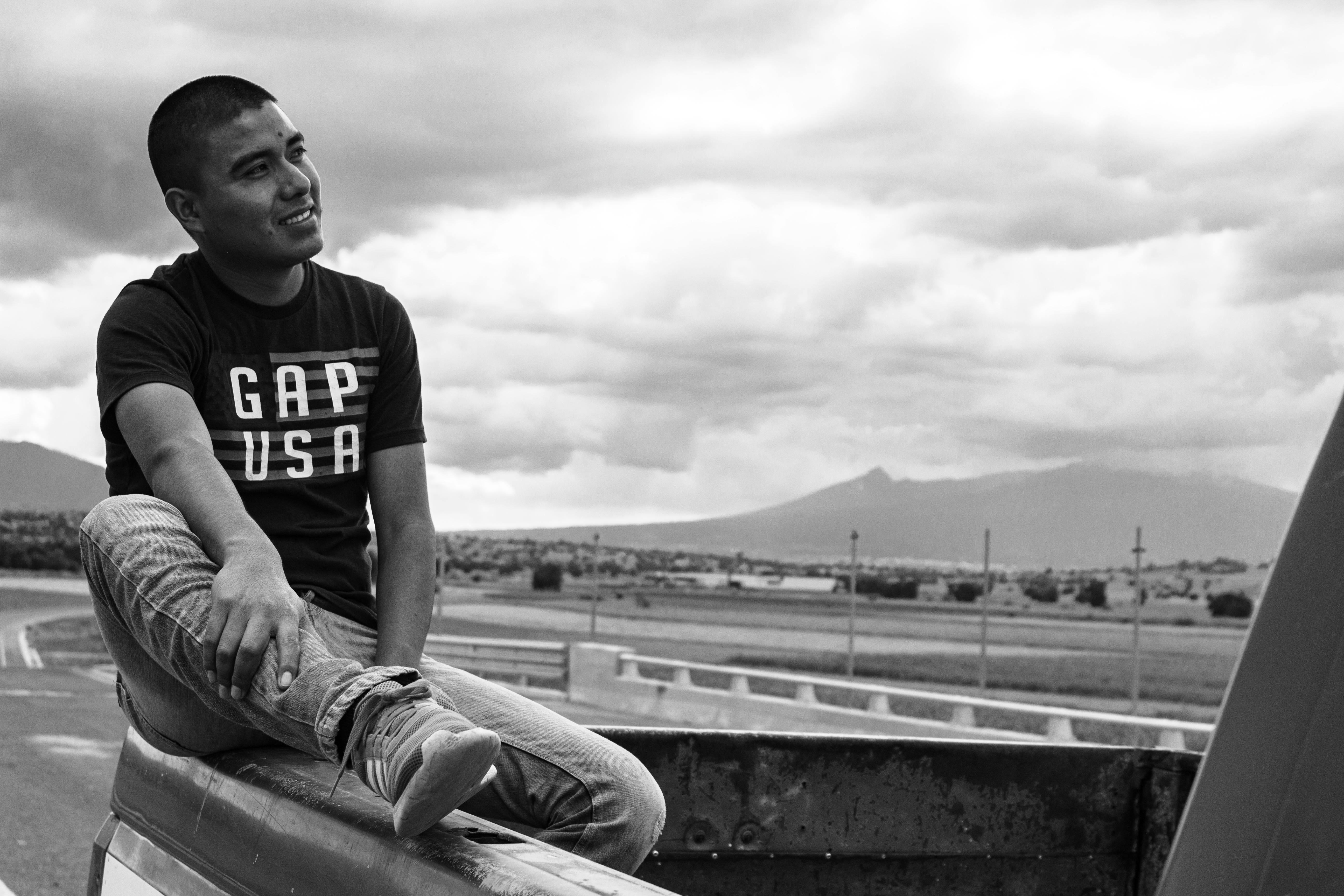 joven masculino feliz sentado mirando al cielo